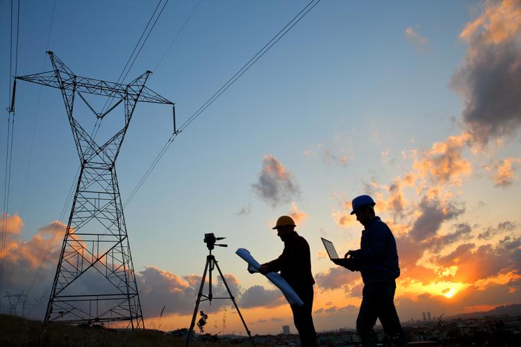 Workers silhouetted near power lines
